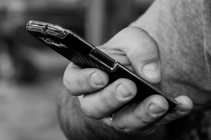 Close-up Hand of the Man that is texting on the cell phone. Electronic Paying online through ebanking.