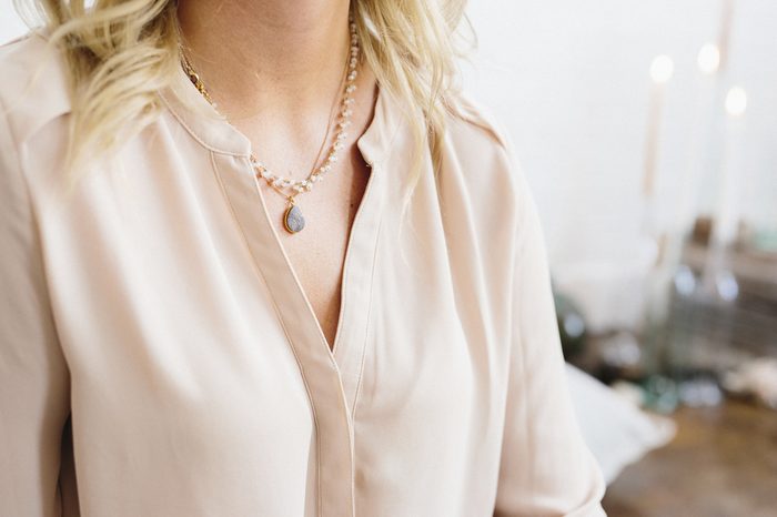 A woman in a silk shirt wearing a pendant necklace