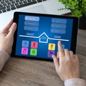 woman hands holding tablet computer with app smart home in room
