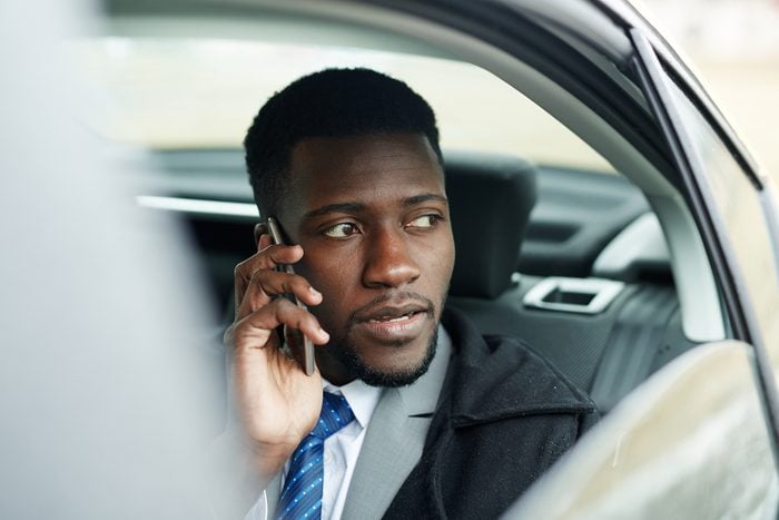 African-american businessman driving car and talking on cellphone