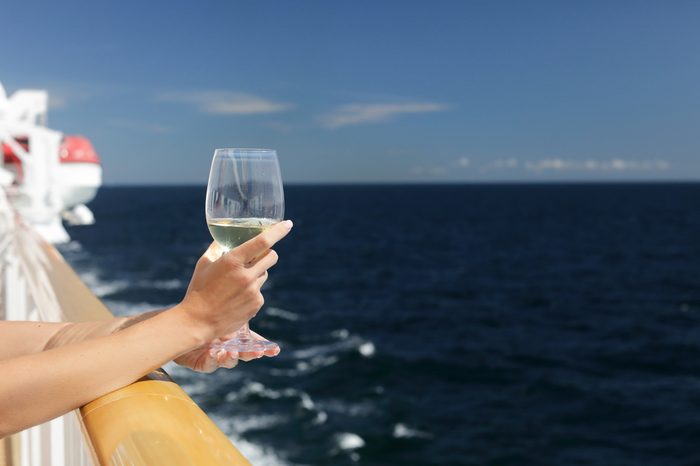 Female hand holds a glass of white wine on a cruise liner