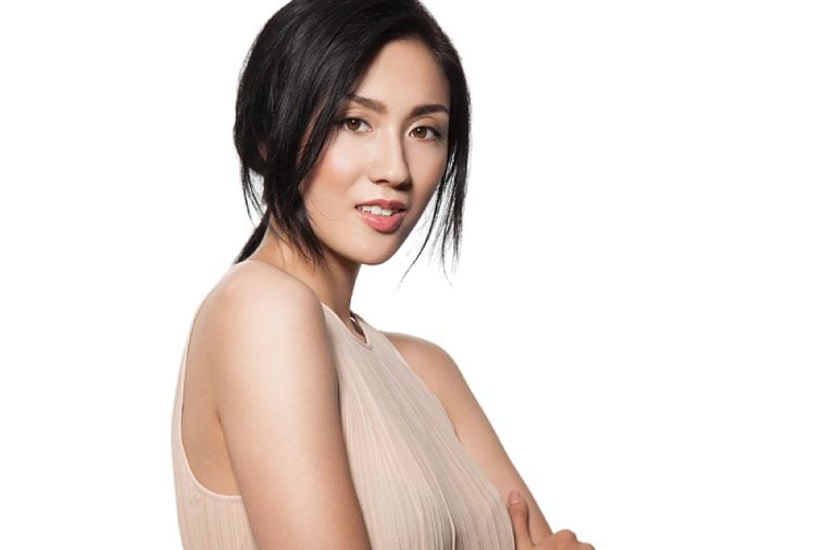 Young stylish asian woman in beige dress with clean skin and natural make-up looks into the camera isolated on white background