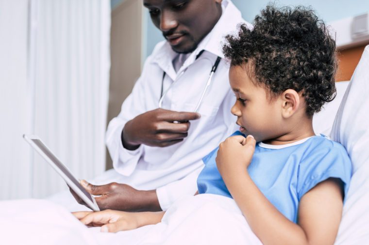 african american doctor and little boy using tablet together in hospital