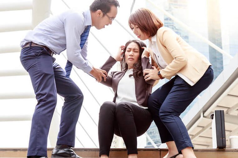 A middle aged business woman is fainted and fallen on floor. Her friends help her and their are shocking. The business woman gets stressed from her work. She faints at the city while goes to office.