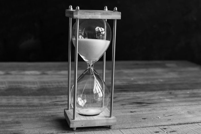 Hourglass or vintage sandglass on wooden background (selective focus)