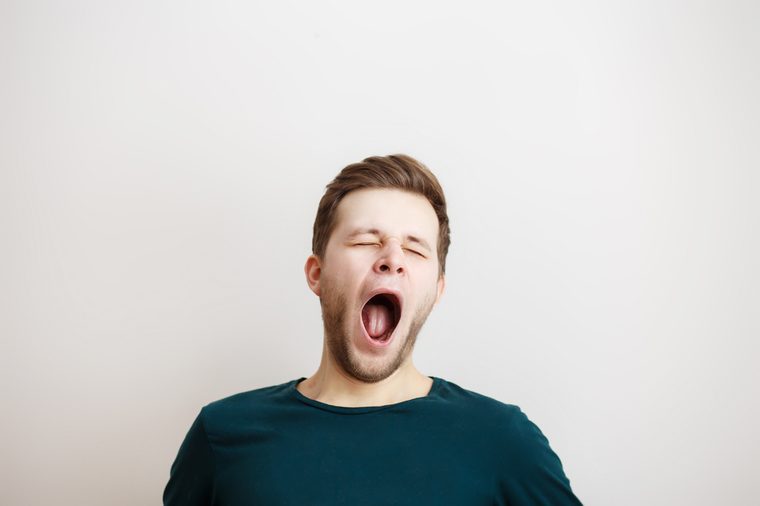 Portrait of yawning man on a light background