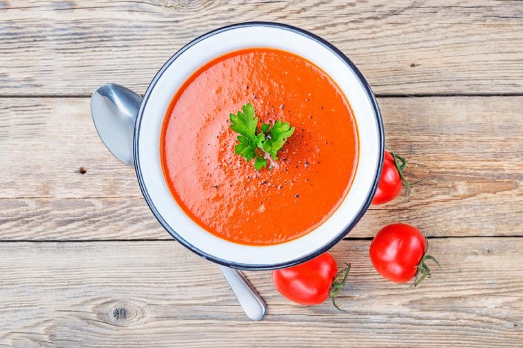 Tomato soup on wooden table, top view