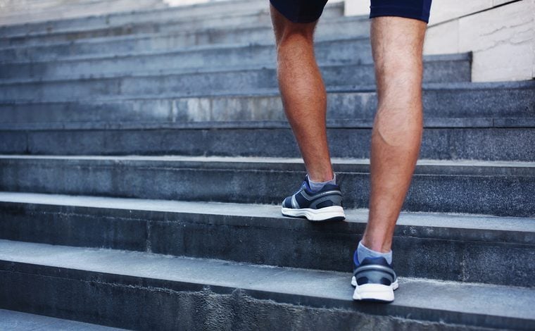 Sport, fitness and healthy lifestyle concept - man running in the city, feet of male runner on steps of stairs closeup over urban background