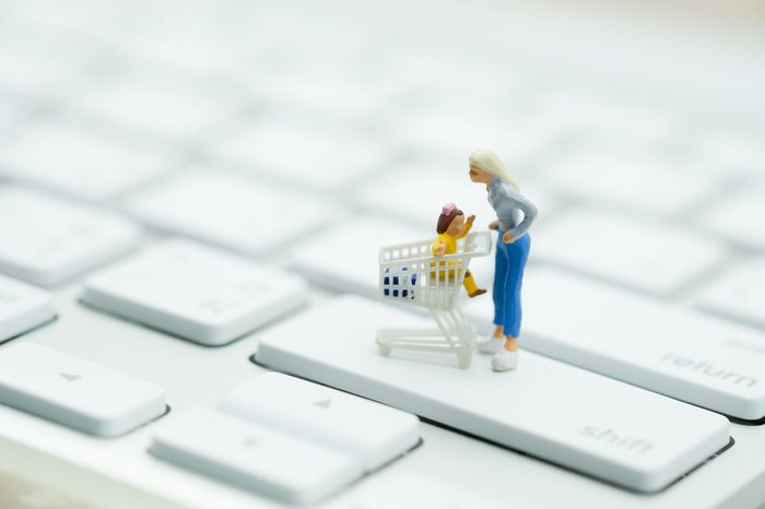 Miniature people: Shopper with shopping cart on keyboard using as background business online concept.