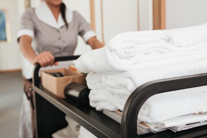 Cropped image of a young hotel maid bringing clean towels and other supplies
