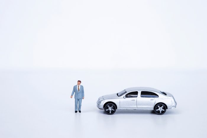 Miniature business man with model car on white background, business concept