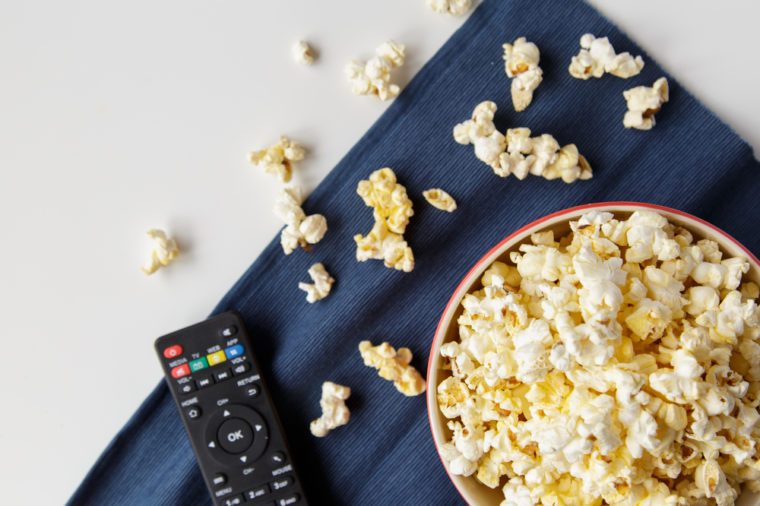 Popcorn with remote control on white table.
