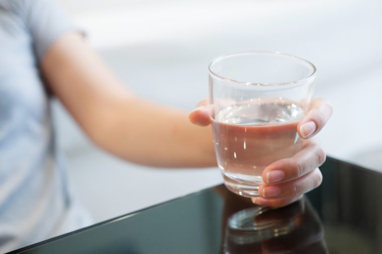 Woman hand holding glass of water for drink.