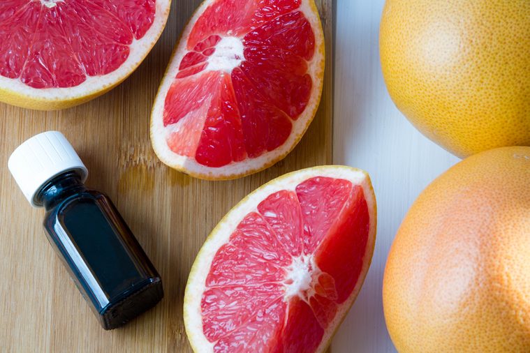 Essential oil in glass bottle with fresh, juicy grapefruit. Spa concept. Selective focus.
