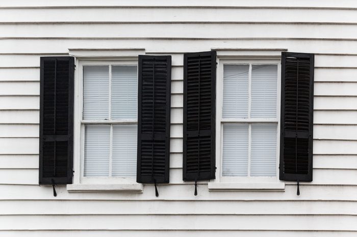 Two shut windows with open blinds on a wooden house