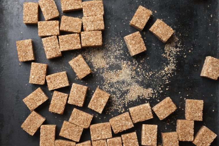 Natural brown sugar cubes on rough black background. Top view point.