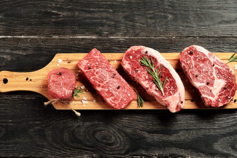 Fresh raw Prime Black Angus beef steaks on a wooden board: Tenderloin, Denver Cut, Striploin, Rib Eye