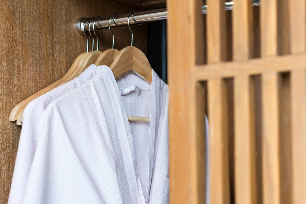 white bathrobe with wooden hangers in wardrobe