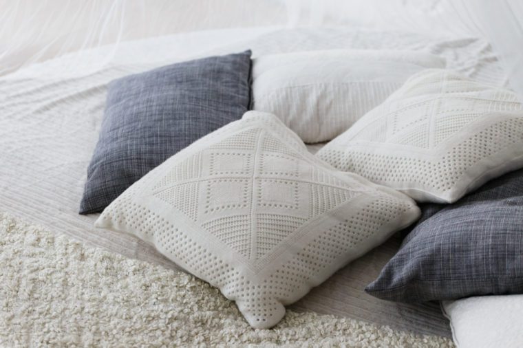 새틴 침구 스타일의 침대에 파스텔 색상, 흰색 및 밝은 회색 쿠션 또는 베개 세팅.