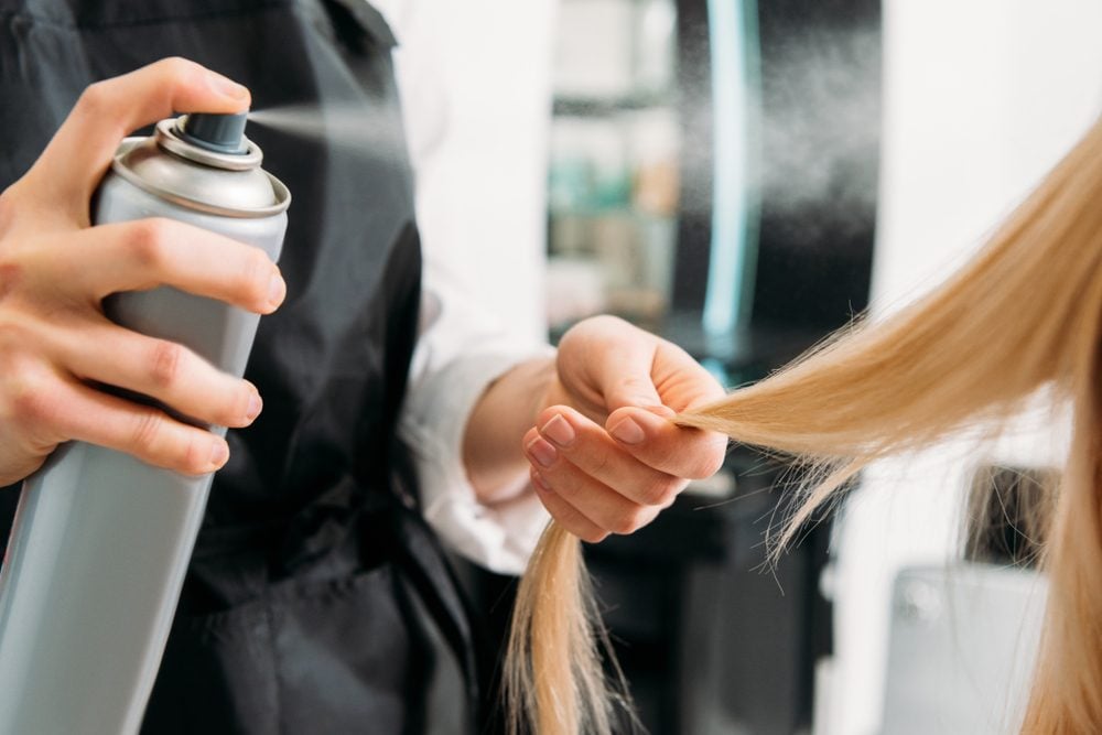 cropped image of hairdresser applying hair spray 