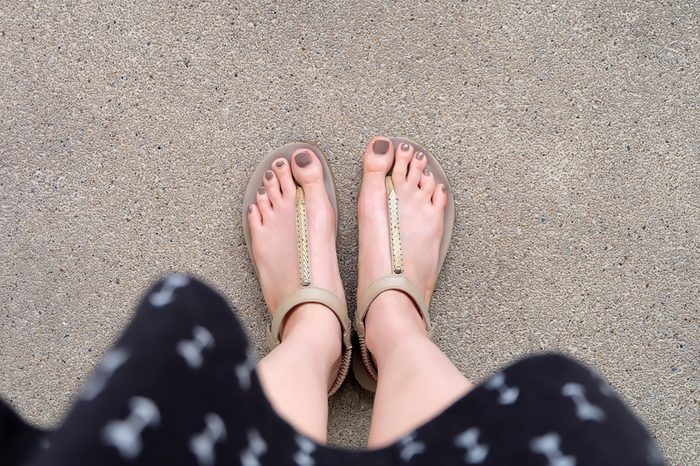 Selfie Feet Wearing Gold Sandals and Dress on Ground Background Great For Any Use.