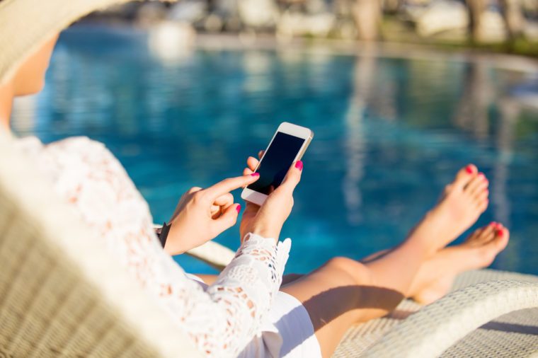 Woman sitting in deck chair and using mobile phone