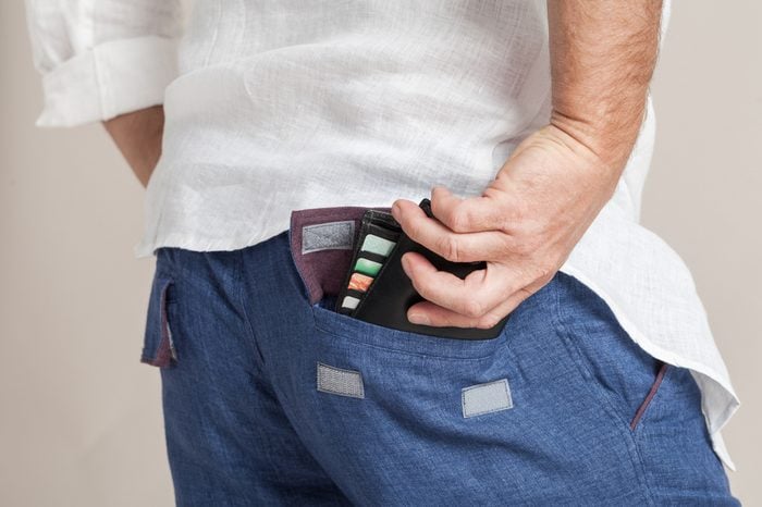 Closeup fashion image of man's hand taking wallet out of his pocket. Body detail of a modern business man. Hand in a pocket with wallet in a loose linen fabric clothes.