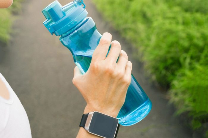 Female runner drinking bottle of water. Health and fitness concept.