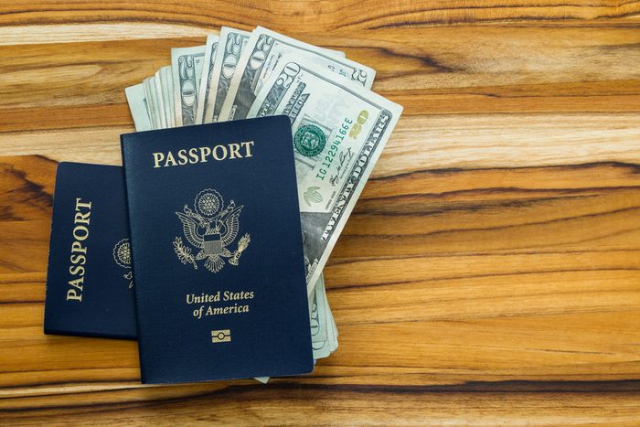 close up of two american passports and cash money on a wooden table for a travel concept
