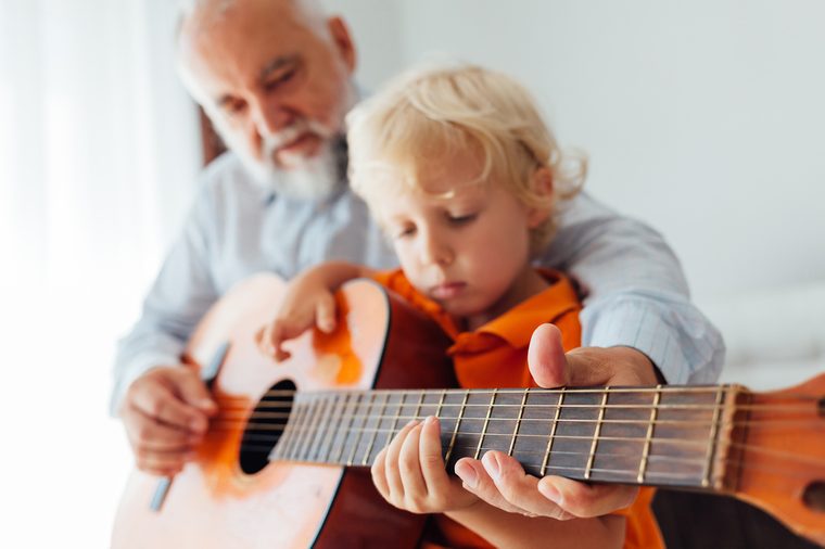 Grandpa learning his grandson to play guitar in closeup