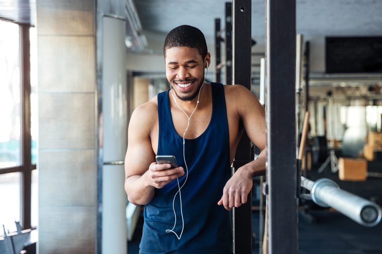 Healthy fitness man using smartphone in the gym, texting message