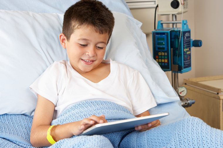 Boy Relaxing In Hospital Bed With Digital Tablet