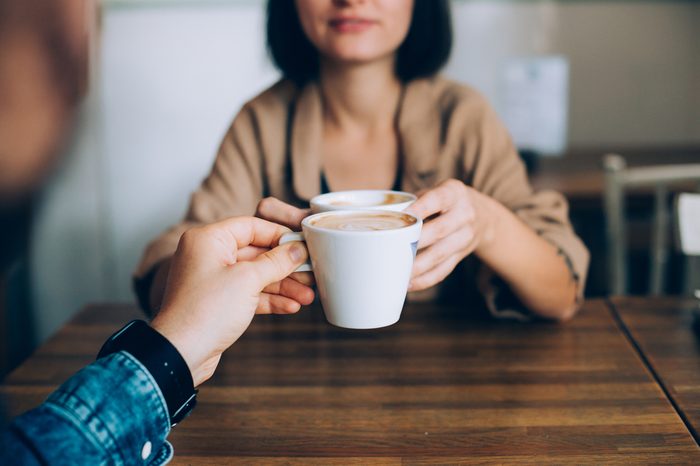 Man proposes gives coffee in white little cup to his girlfriend or partner, they are in love and are on romantic date in downtown stylish cafe or restaurant, drink artisan specialty 