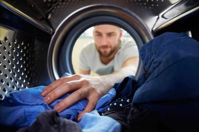 Man Doing Laundry Reaching Inside Washing Machine