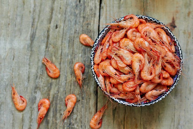 Prepared shrimp on blue plate on wooden background