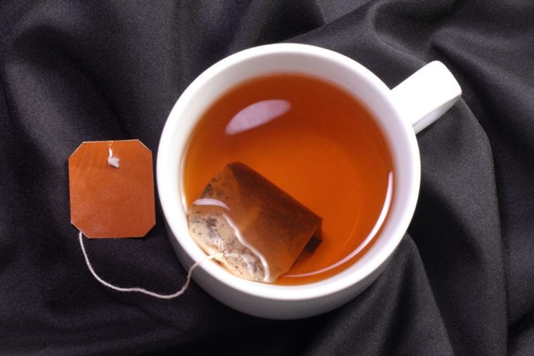 A cup of tea with tea bag on a black simple background