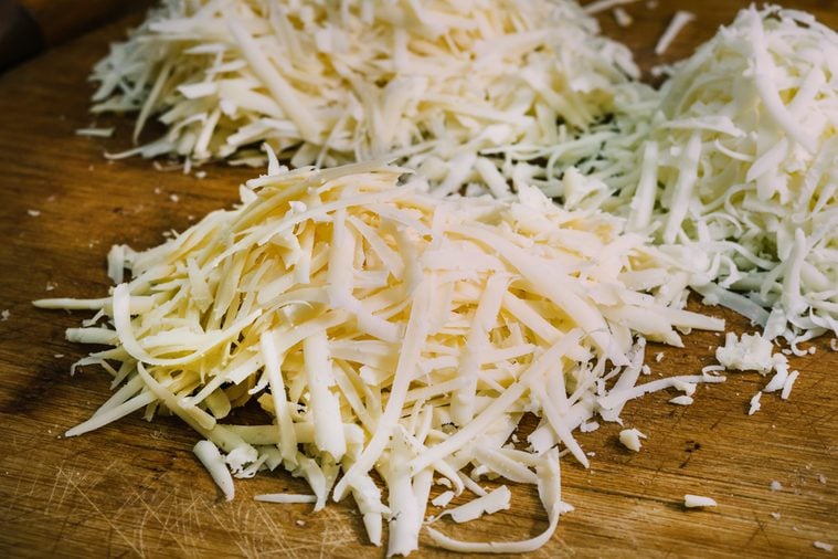 Three different kinds of grated cheese on a wooden board. The concept of cooking.
