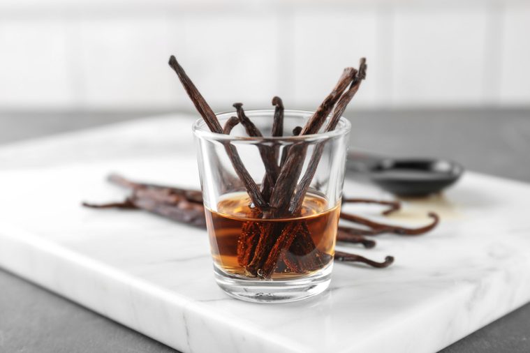 Glass with vanilla extract and dried beans on board