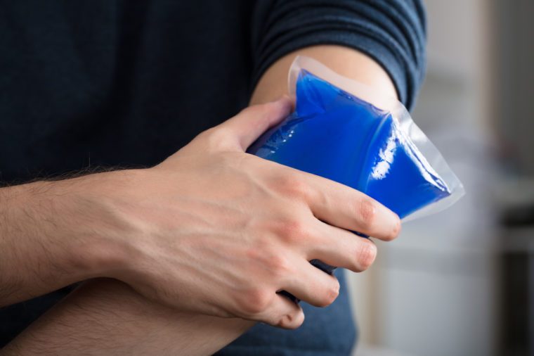 Close-up Of A Person Applying Ice Gel Pack On An Injured Elbow At Home