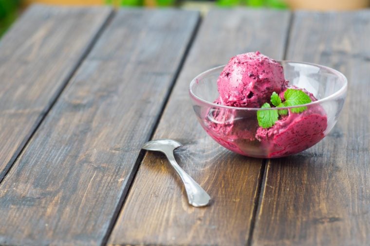 Homemade blueberry ice cream or sorbet served in a glass dish on wooden table in rustic style