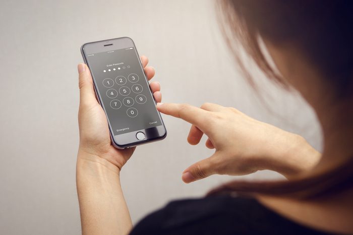 Close up woman hand holding smartphone while entering the passcode.