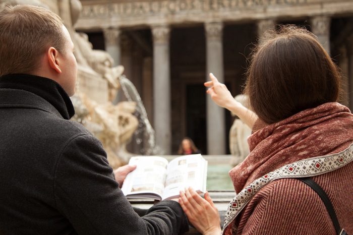 Unrecognizable young couple of travelers looking at Pantheon and holding touristic guide