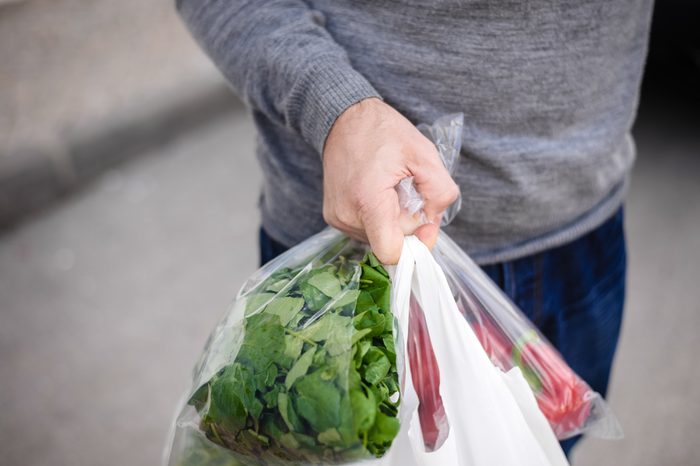 Male carrying bag in his hand after shopping. Closeup of bag full of fruits and vegetables. 