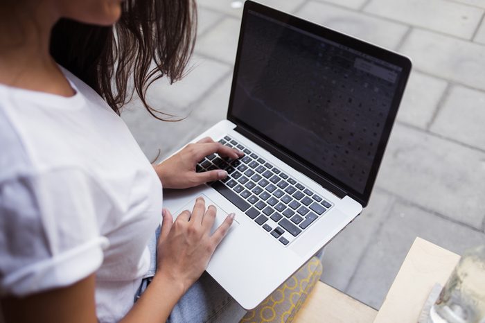 Cropped image of women's hands keyboarding on her laptop computer while sitting in restaurant in the fresh air,young female using net-book with blank copy space screen for your text message or content