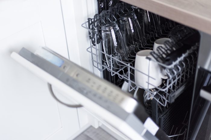 close up of open dishwasher with clean glasses and dishes