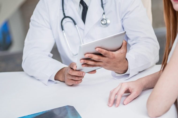 Checking medical tests. Serious doctor and patient. Doctor holding tablet and talking with a patient in the hospital. Close-up view of the hands and the tablet.