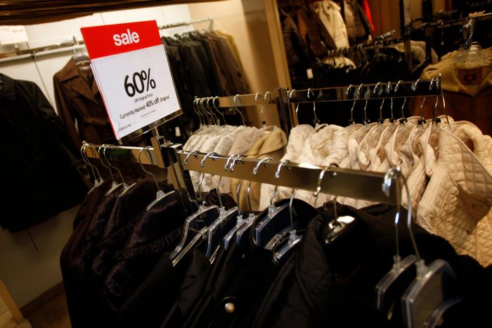 A discount sign stands on top of a rack of coats on sale at a Macy's department store