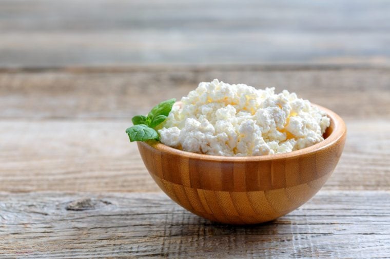 Homemade cottage cheese in a bowl on old wooden table.