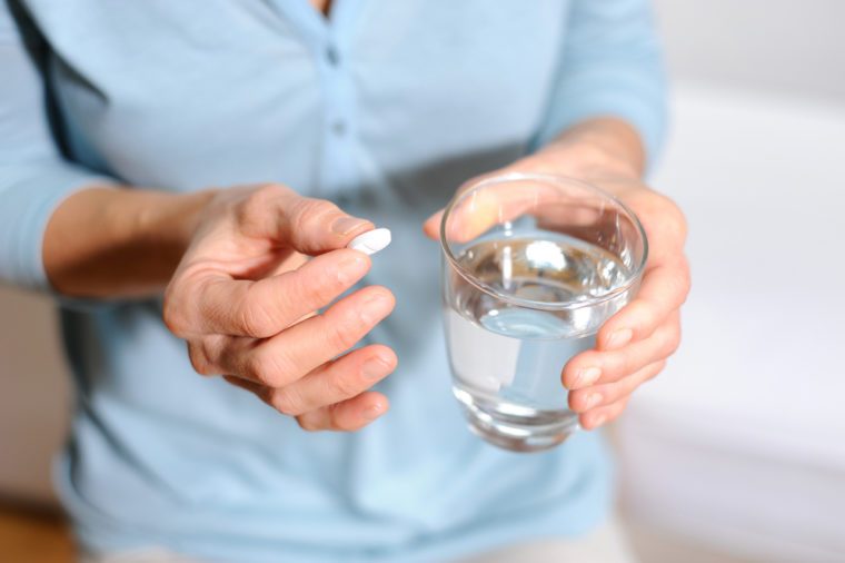 Woman is taking a pill with a glass of water