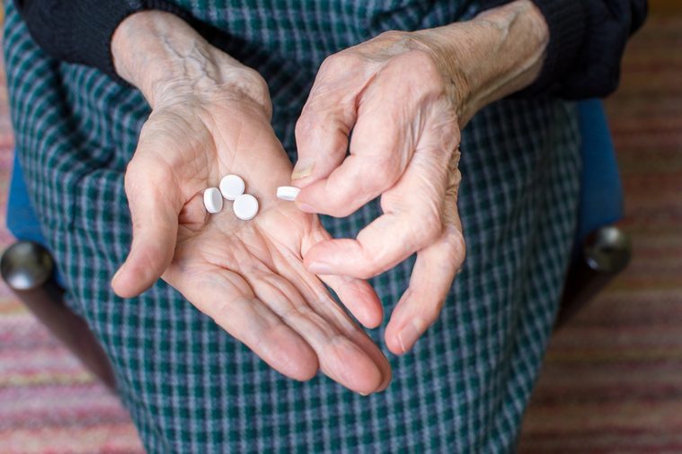Hands of very old woman taking pills